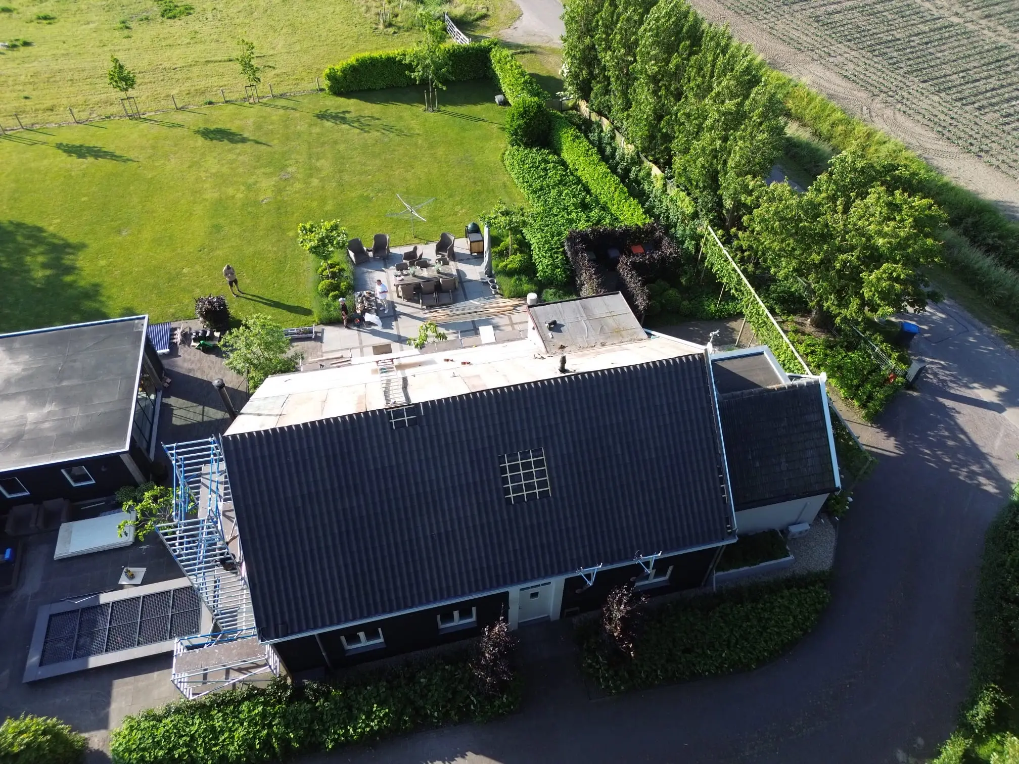 Dakrenovatie in uitvoering, half vernieuwd pannendak gezien vanuit de lucht
